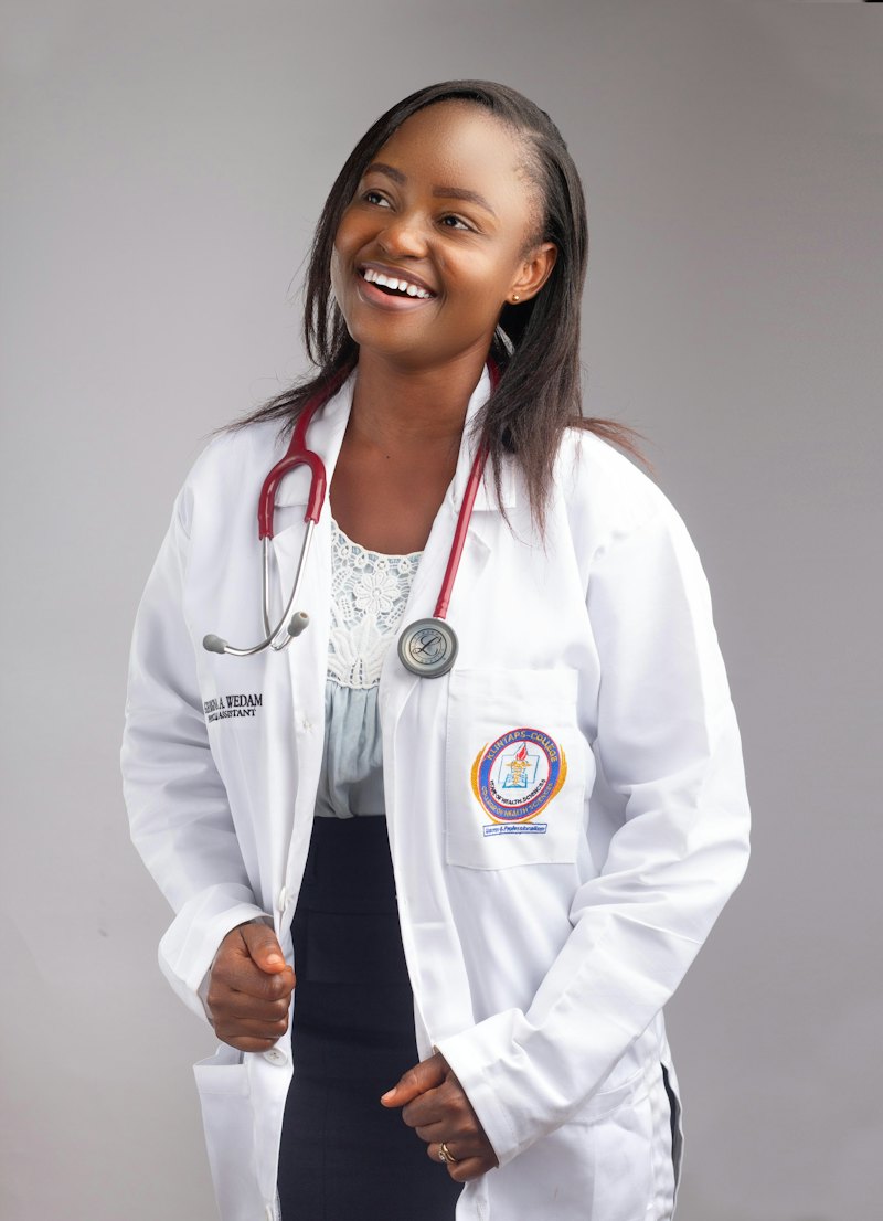 A smiling young Black pharmacist in a white coat with a stethoscope